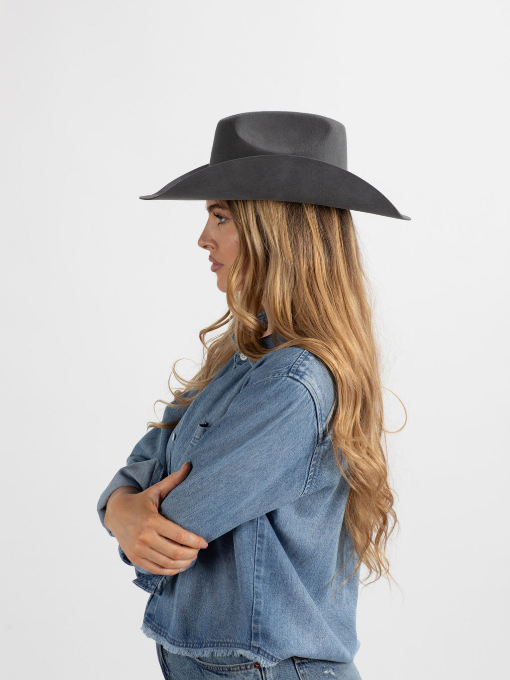 Woman wearing aBurera beaded cowboy hat and denim jacket on a white background