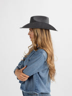 Woman wearing aBurera beaded cowboy hat and denim jacket on a white background